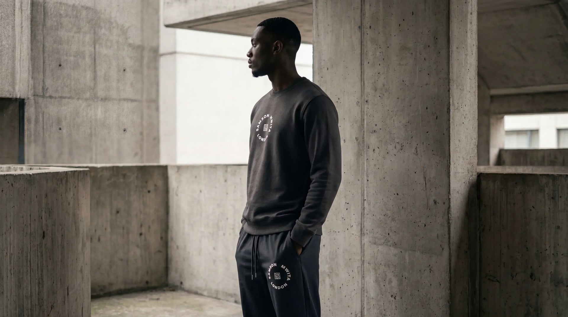 Model wearing SM London Sweatshirt and Sweat pants outdoor in concrete backdrop