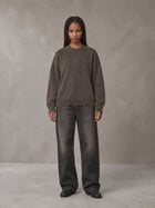 Model wearing the SM Sig. Washed Distress Knit Sweater in Kabul Brown with SM Archive Fade Denim Jeans in black, front view.
