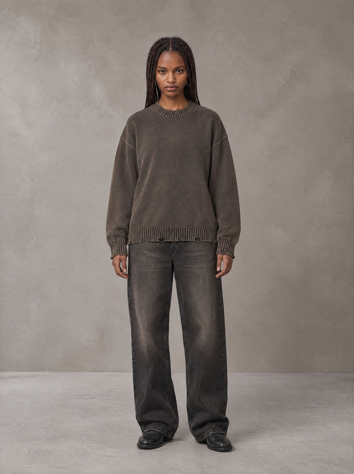 Model wearing the SM Sig. Washed Distress Knit Sweater in Kabul Brown with SM Archive Fade Denim Jeans in black, front view.
