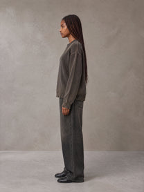 Model wearing the SM Sig. Washed Distress Knit Sweater in Kabul Brown with SM Archive Fade Denim Jeans in black, side profile.