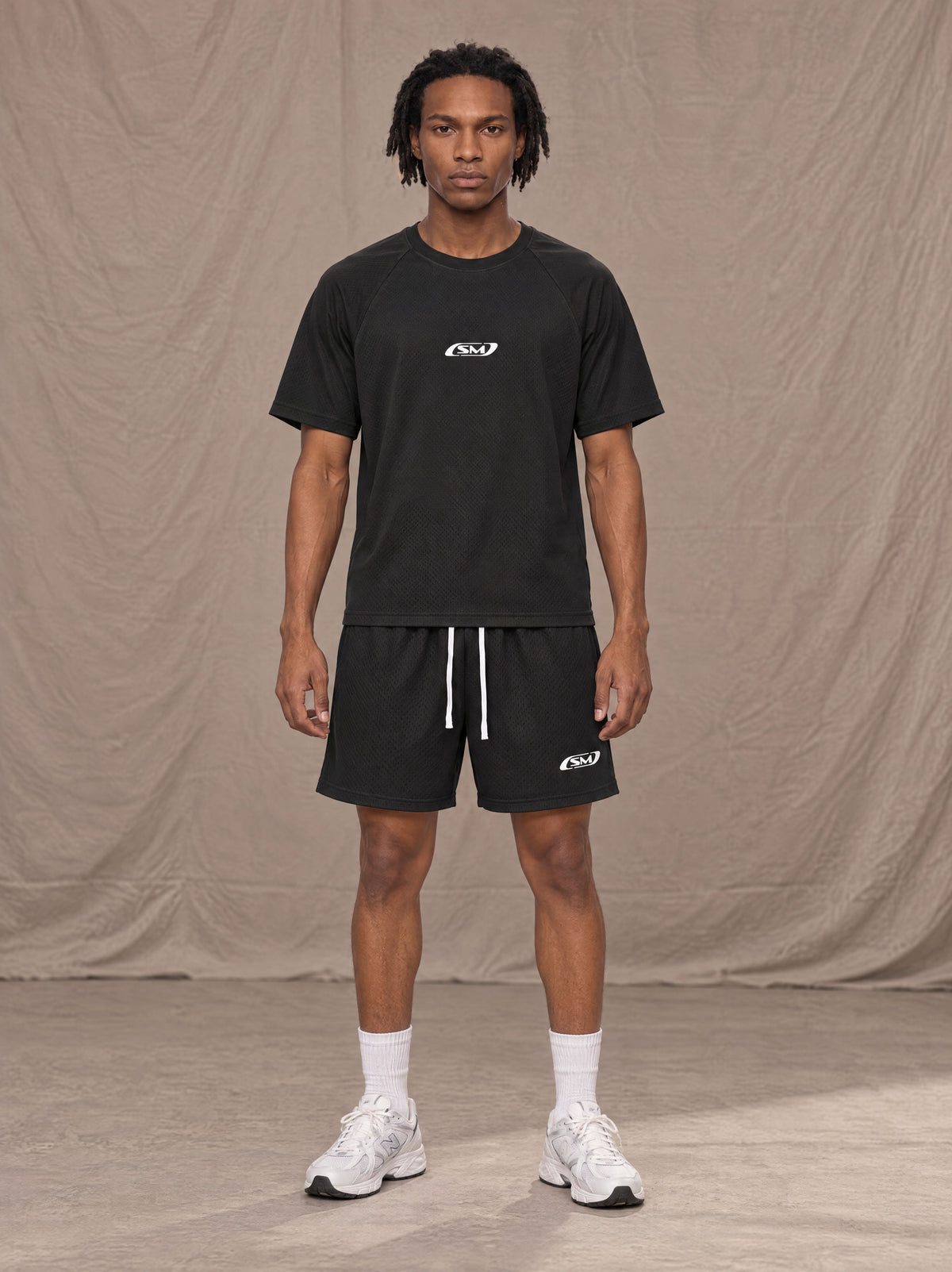 Model wearing the SM Motion Mesh T-shirt and SM Motion Mesh Shorts in black, front view.