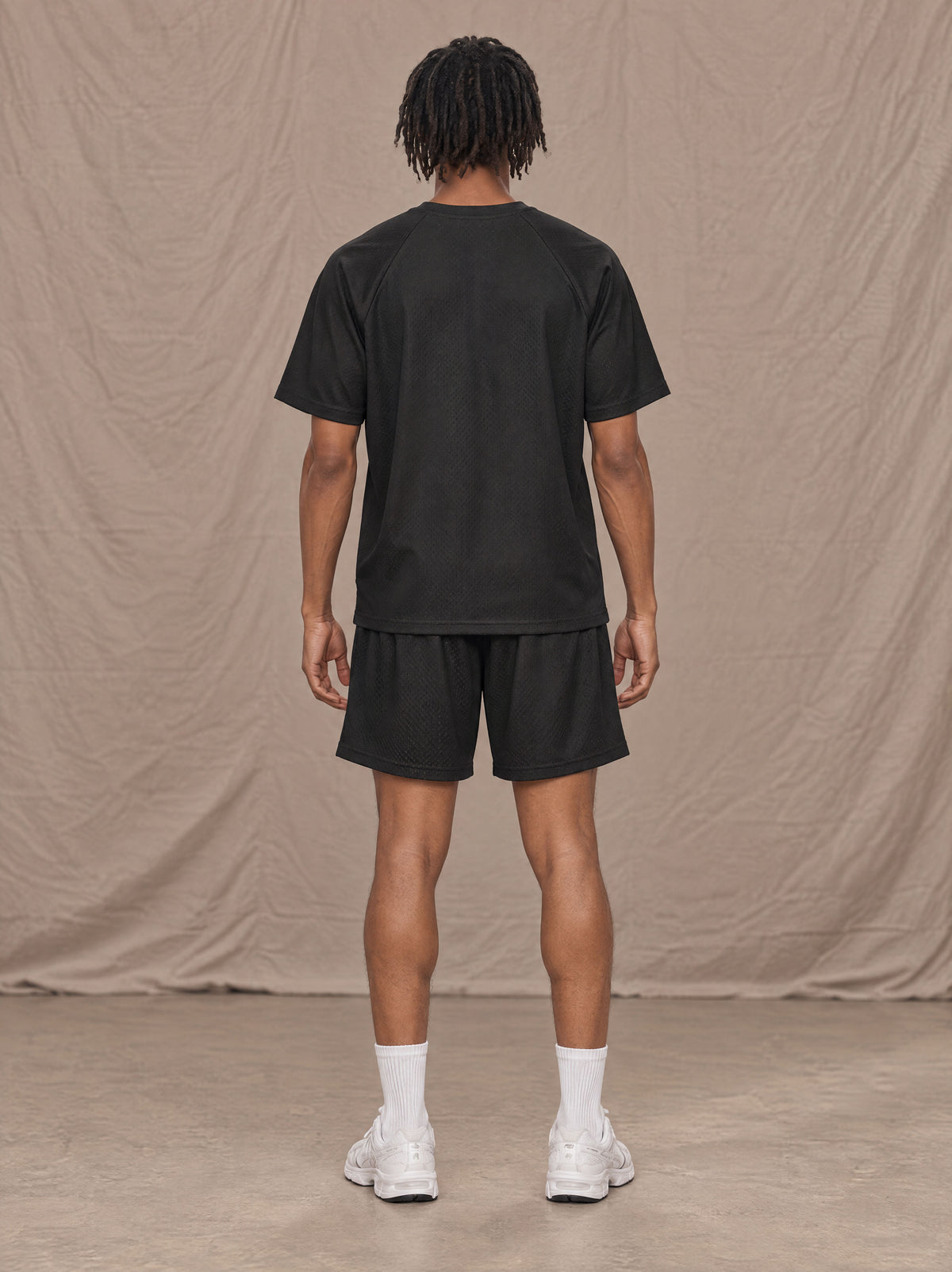 Model wearing the SM Motion Mesh T-shirt and SM Motion Mesh Shorts in black, rear view.