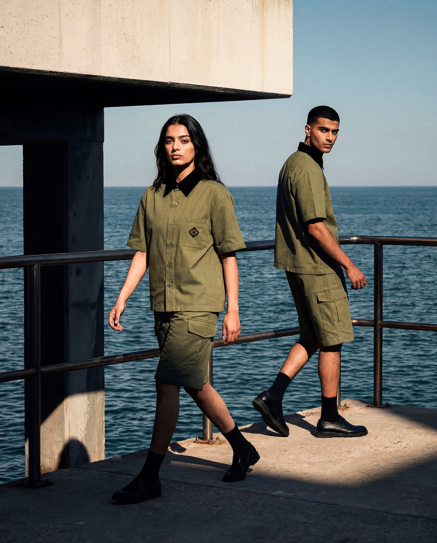 Two models in matching SM Seternal Fleur olive outfits standing by a body of water.
