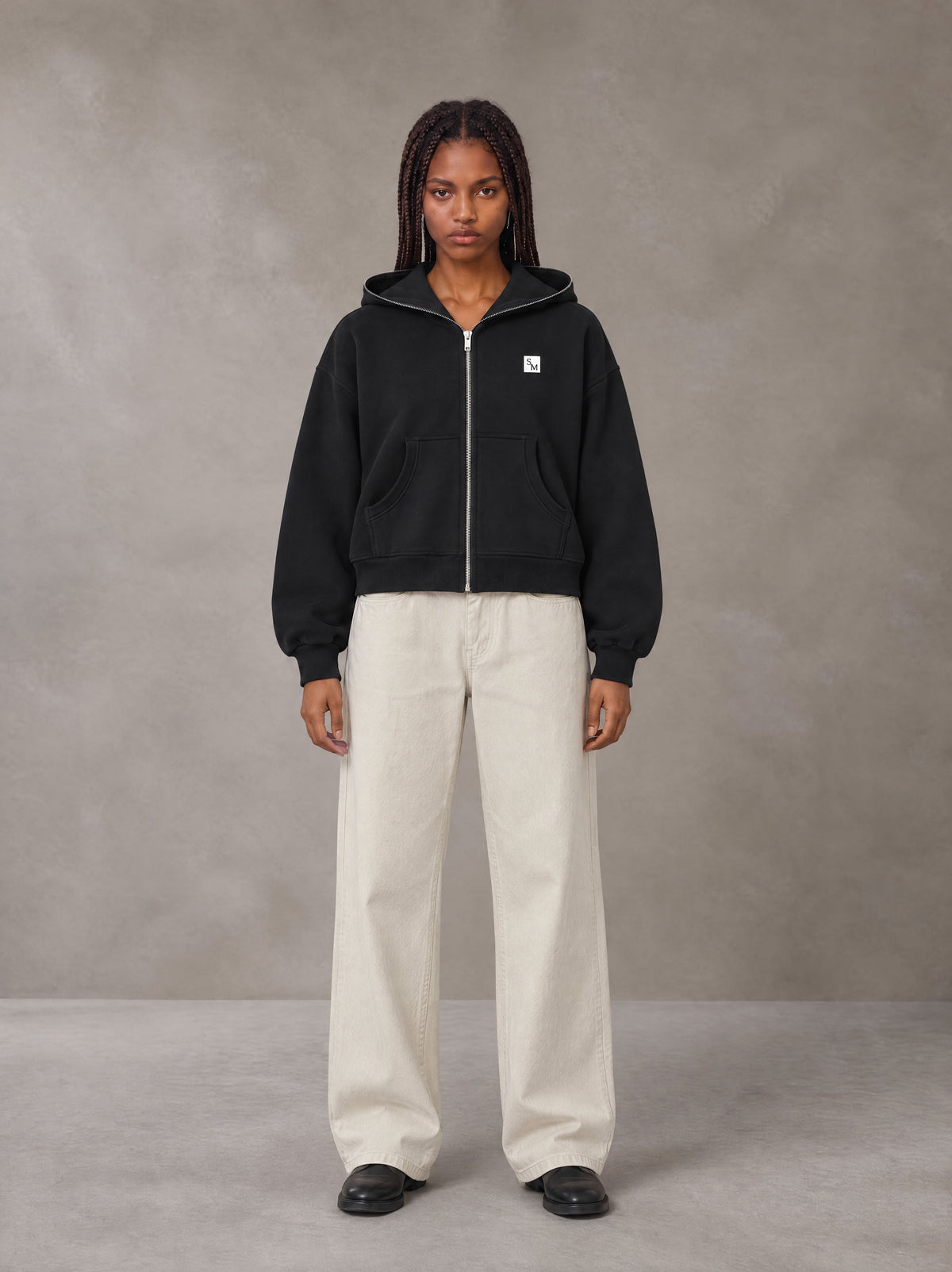 Model wearing SM Sig. Full-Zip Boxy Hoodie in Midnight Black, front view.