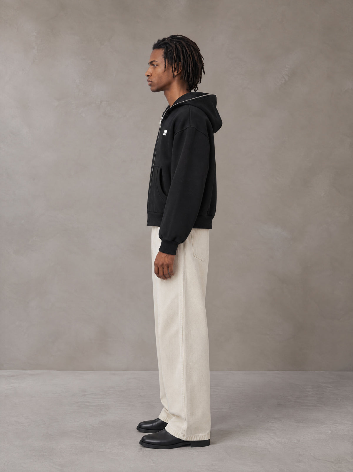 Model wearing SM Sig. Full-Zip Boxy Hoodie in Midnight Black, side view.