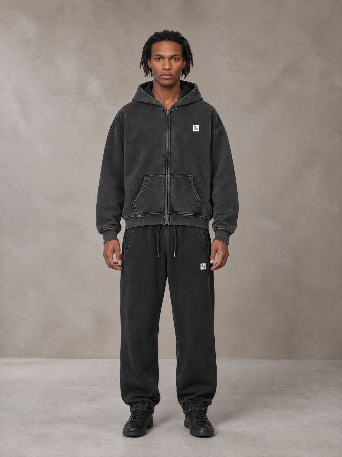 Model wearing the SM Sig. Boxy Hoodie with SM Sig. Jogger Sweatpants in Midnight Black, front view.