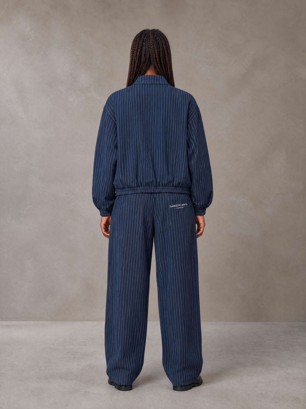 Model wearing the SM Axis Jacket and SM Axis Trousers in Oxford Navy, rear view.