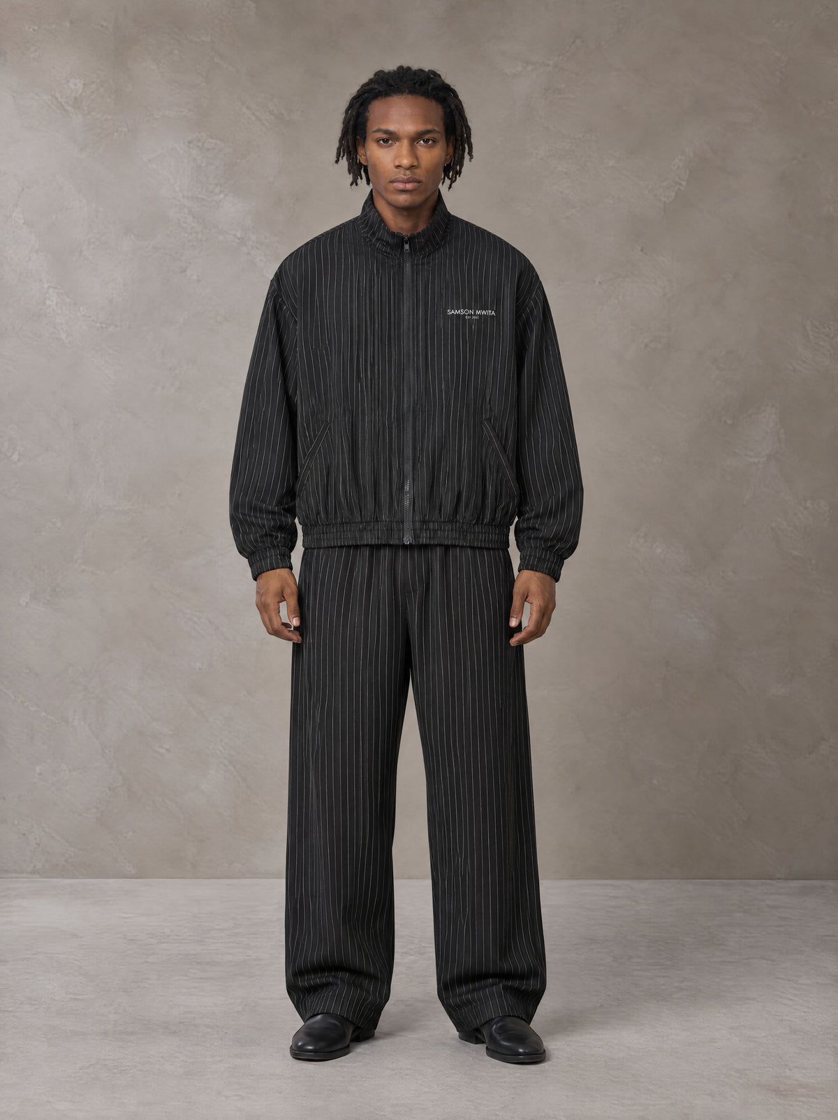 Model wearing the SM Axis Jacket and SM Axis Trousers in Midnight Black, front view.