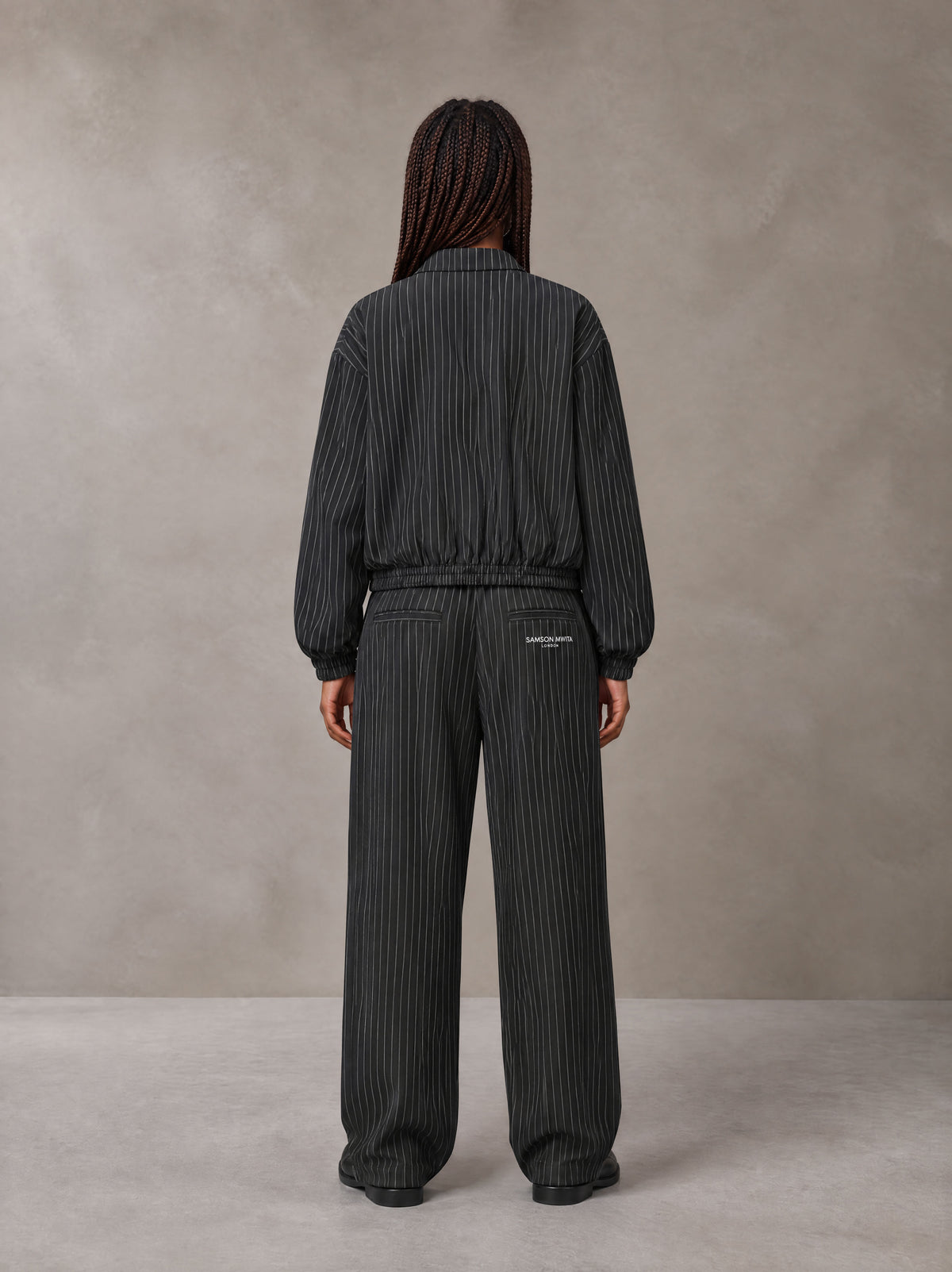 Model wearing the SM Axis Jacket and SM Axis Trousers in Midnight Black, rear view.