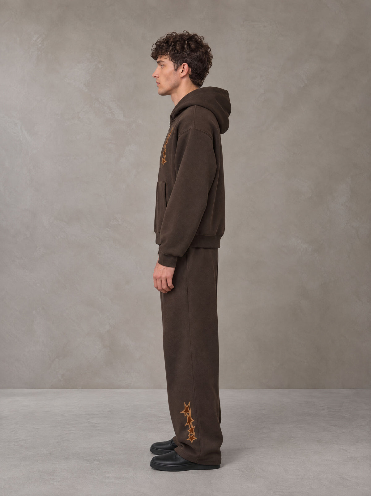 Model wearing the SM Shadow Pulse Hoodie and SM Shadow Pulse Sweatpants in Kabul Brown, side profile.