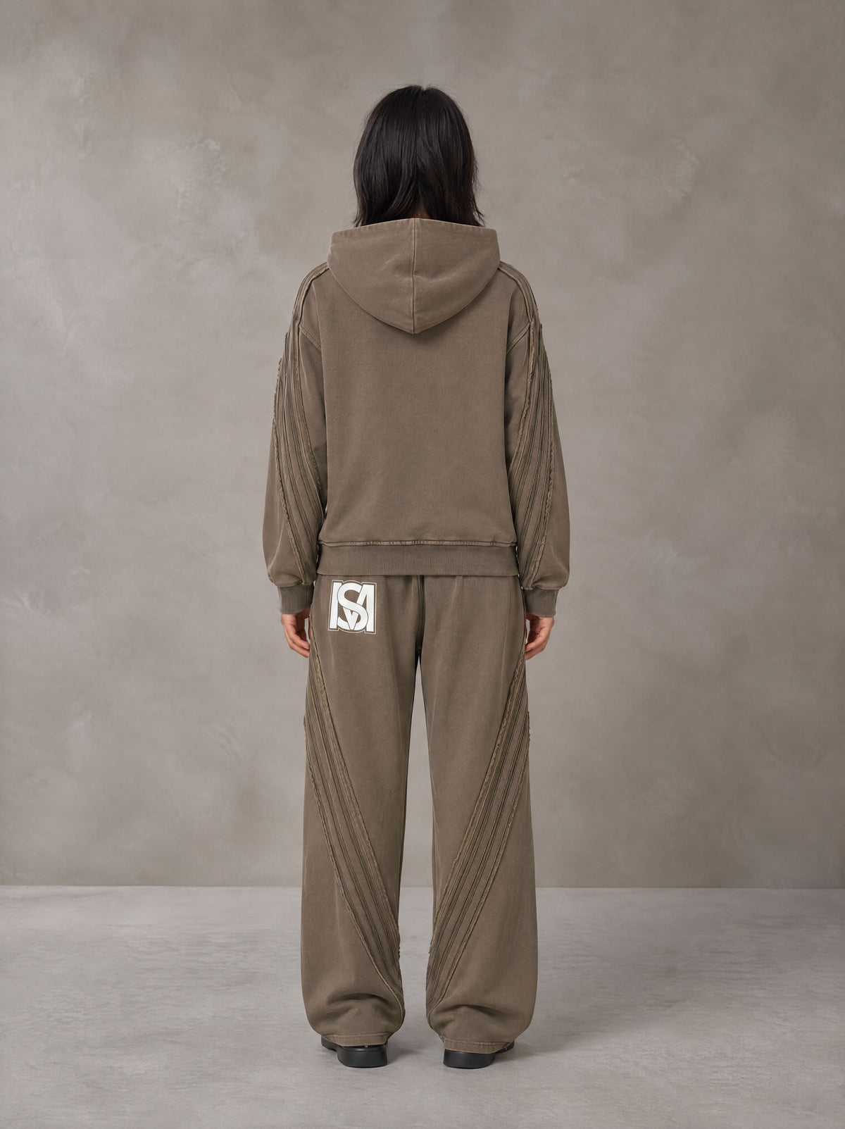 Model wearing the SM Arc Hoodie and SM Arc Sweatpants in Deep Coffee, rear view.