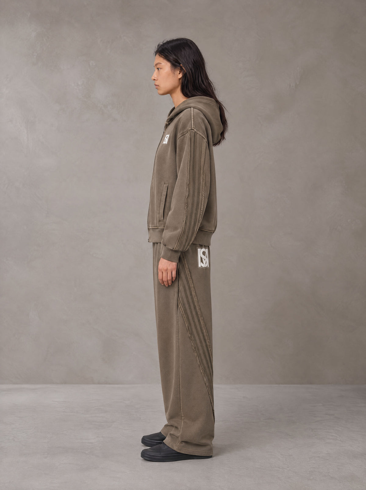 Model wearing the SM Arc Hoodie and SM Arc Sweatpants in Deep Coffee, side profile.