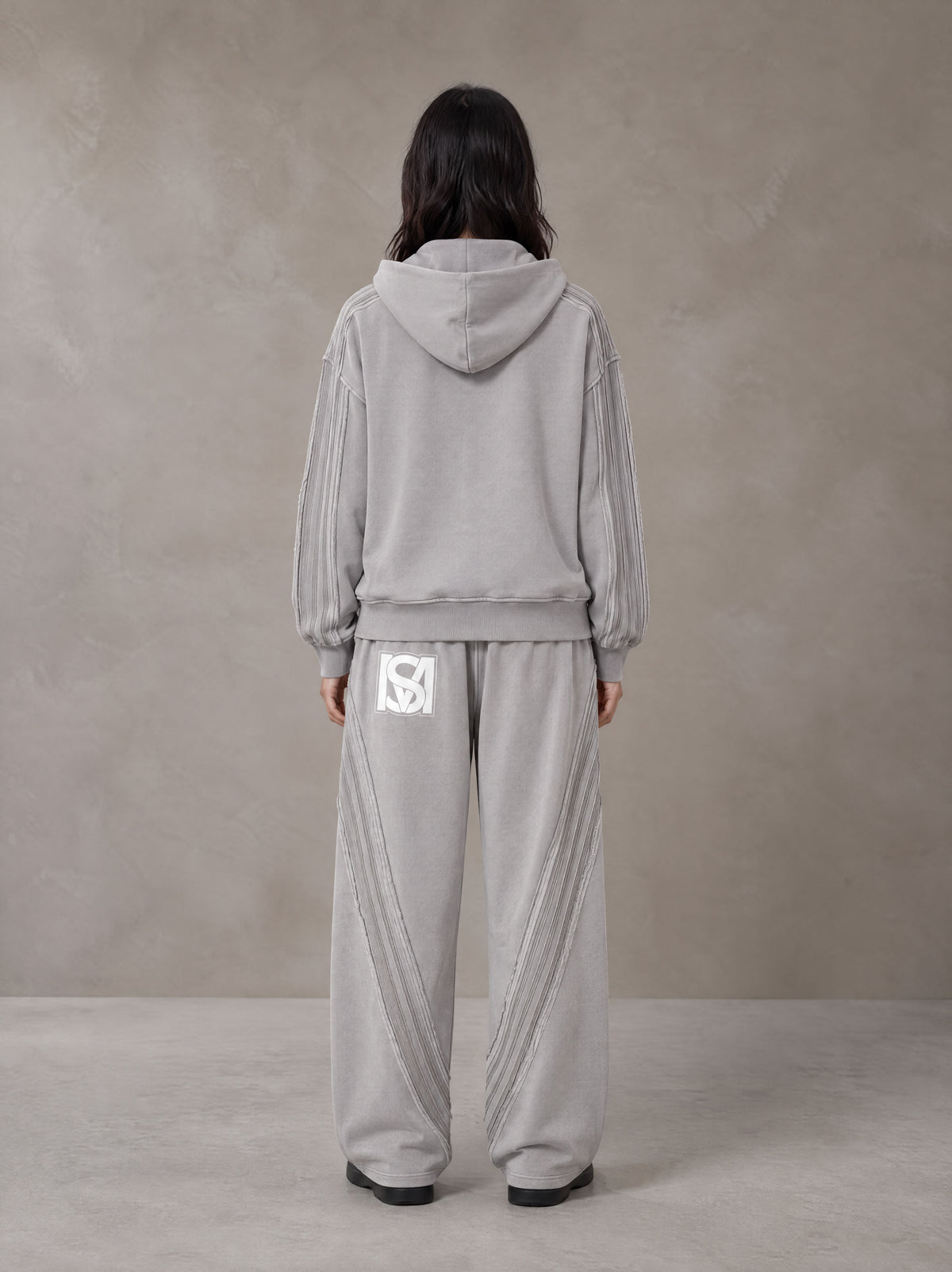 Model wearing the SM Arc Hoodie and SM Arc Sweatpants in Floral Grey, rear view.