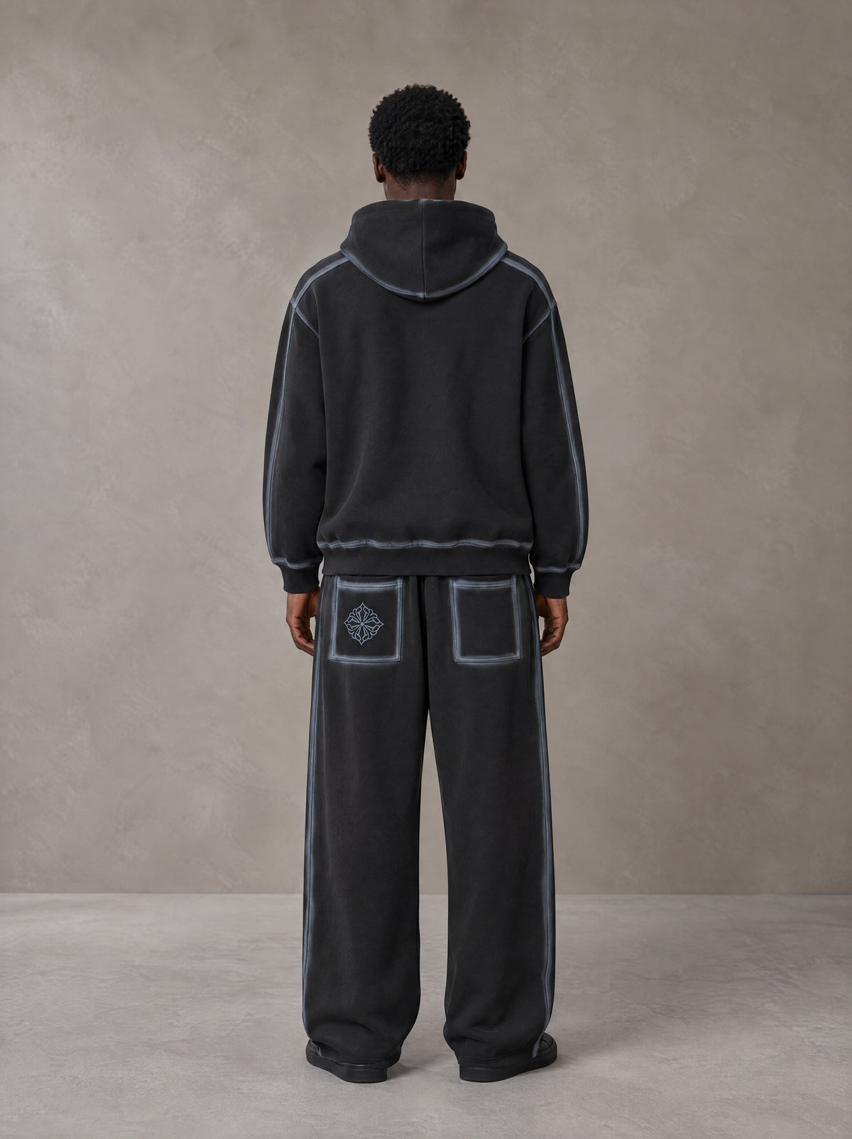 Model wearing the SM Grid Fleur Hoodie and SM Grid Fleur Sweatpants in Deep Charcoal, rear view.