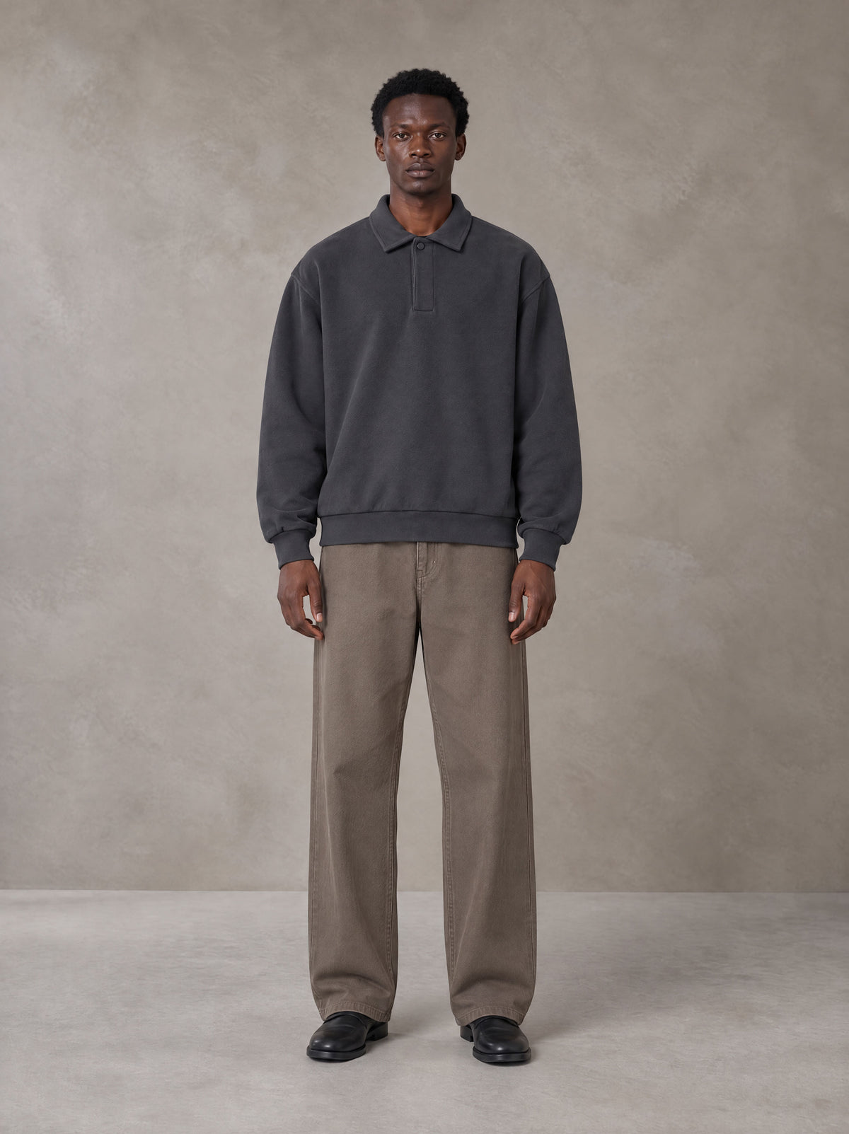 Model wearing SM Sig. Fleece Polo Sweatshirt in Deep Charcoal, front view.