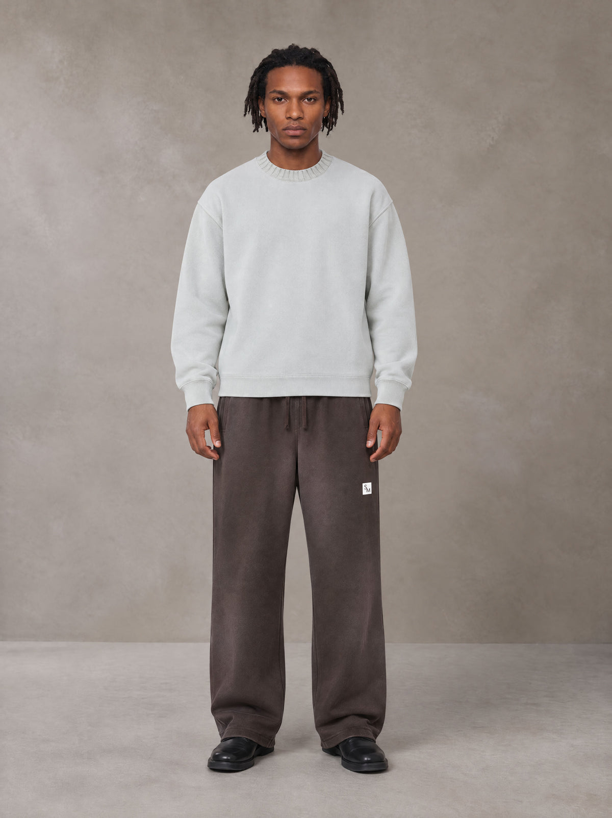 Model wearing SM Sig. Sun Fade Sweatpants in Kabul Brown, front view.