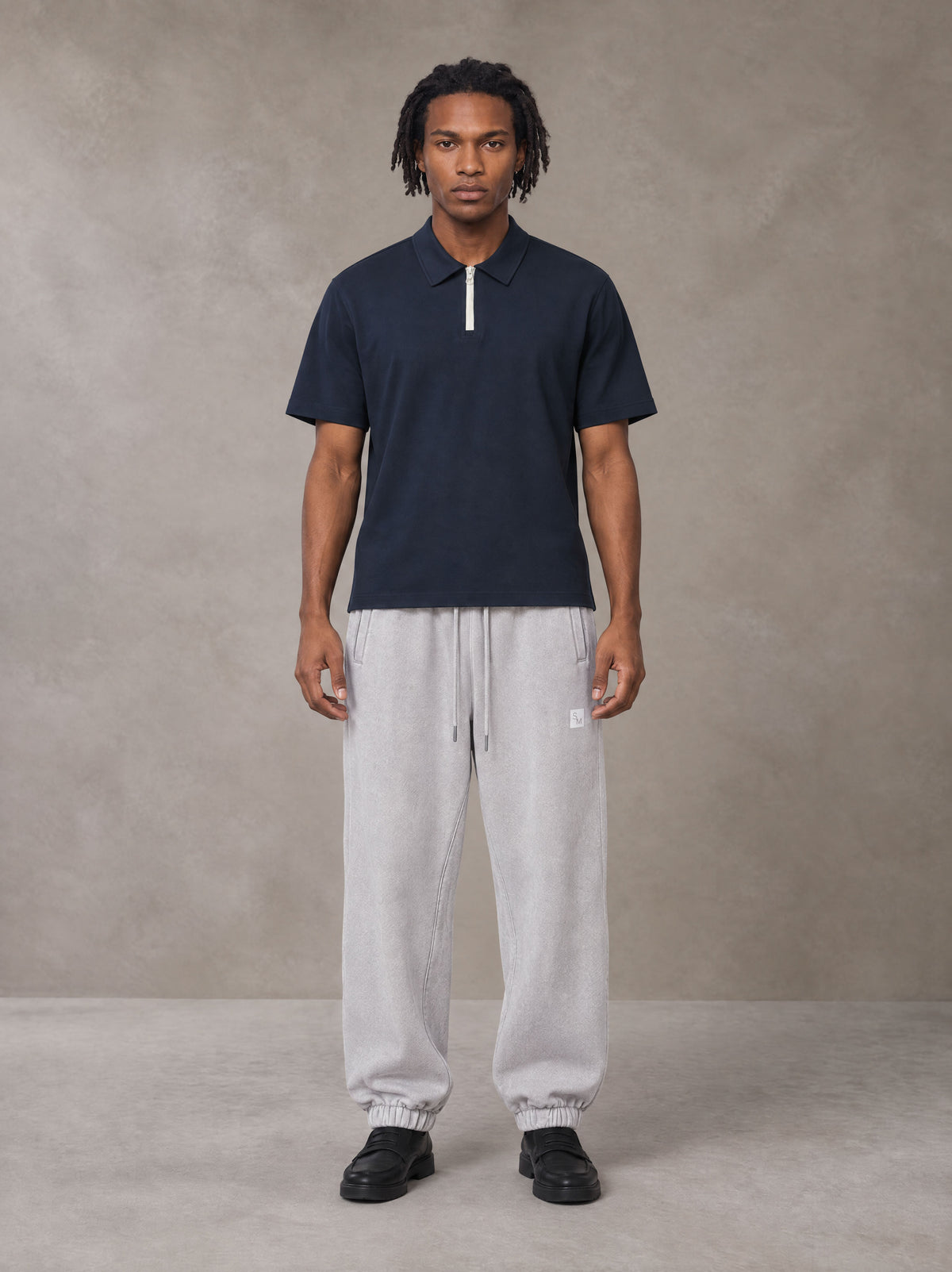 Model wearing SM Sig. Jogger Sweatpants in Floral Grey, front view.