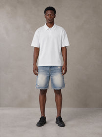 Model wearing SM Heritage Distressed Denim Shorts in Cadet Grey, front view.