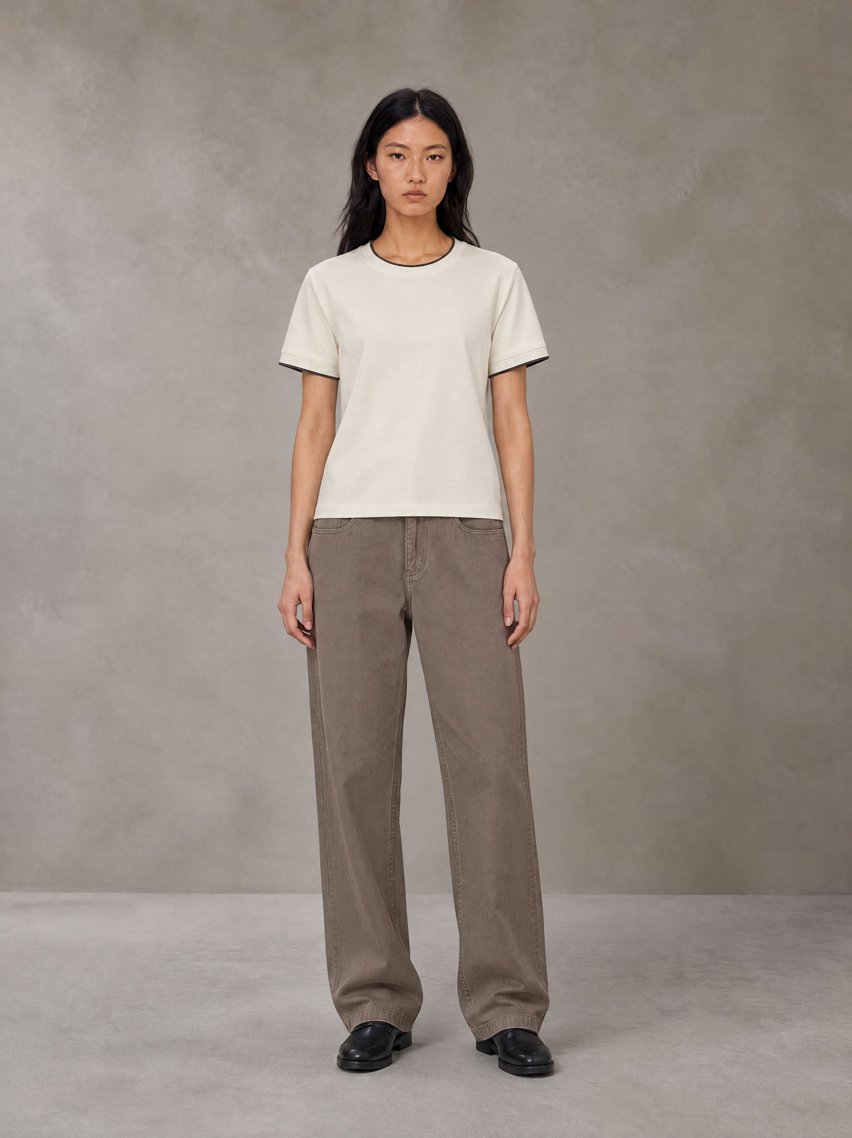 Model wearing SM Sunwash T-shirt in Oat Grey, front view.