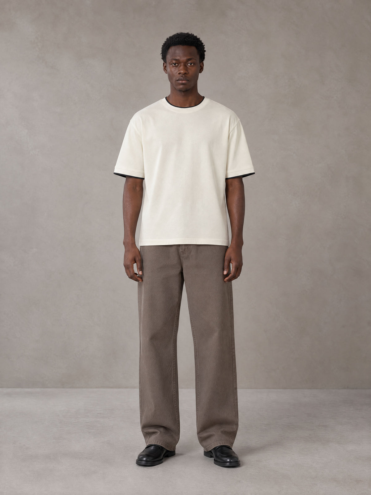 Model wearing SM Sunwash T-shirt in Oat Grey, front view.