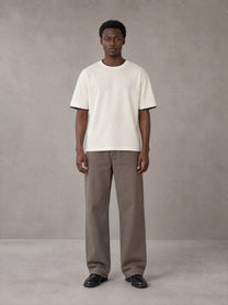 Model wearing SM Sunwash T-shirt in Oat Grey, front view.