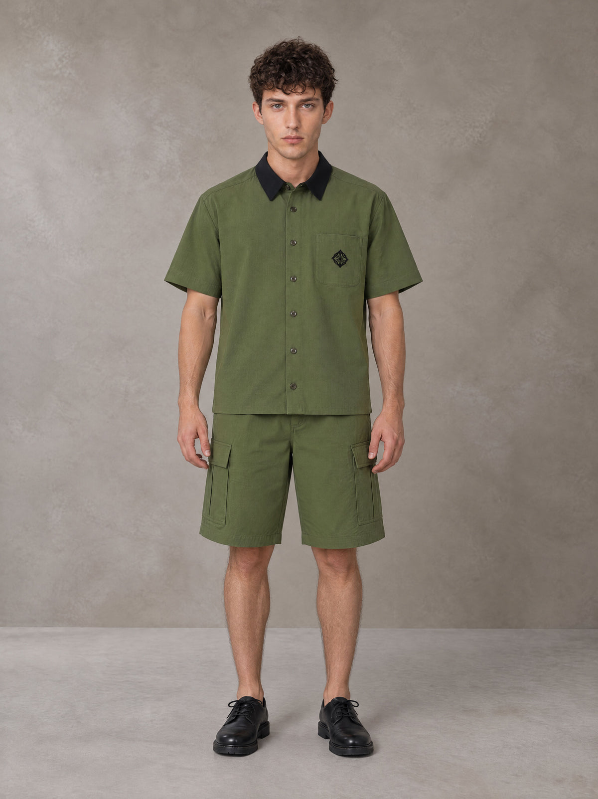 Model wearing SM Eternal Fleur Shirt in Camo Green with SM Eternal Fleur Utility Shorts in Camo Green, front view.