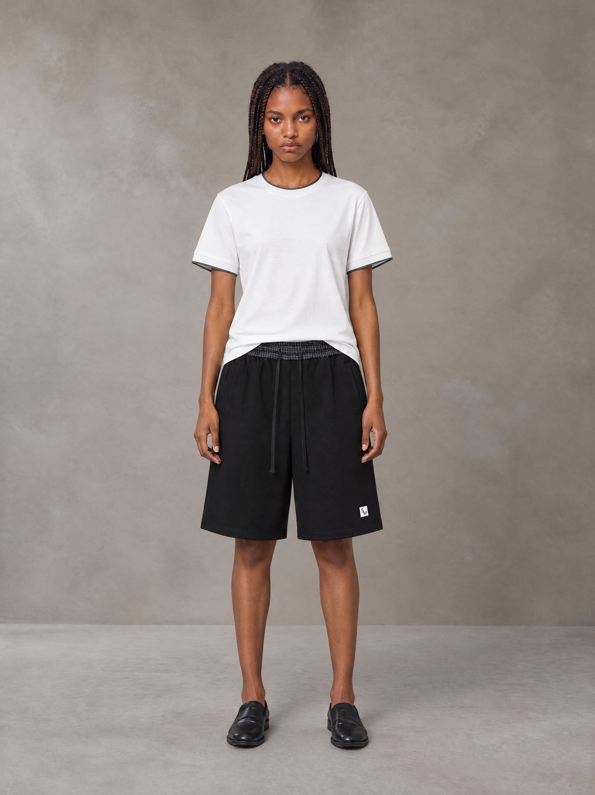 Model wearing SM Plaid Shorts in Midnight Black, front view.