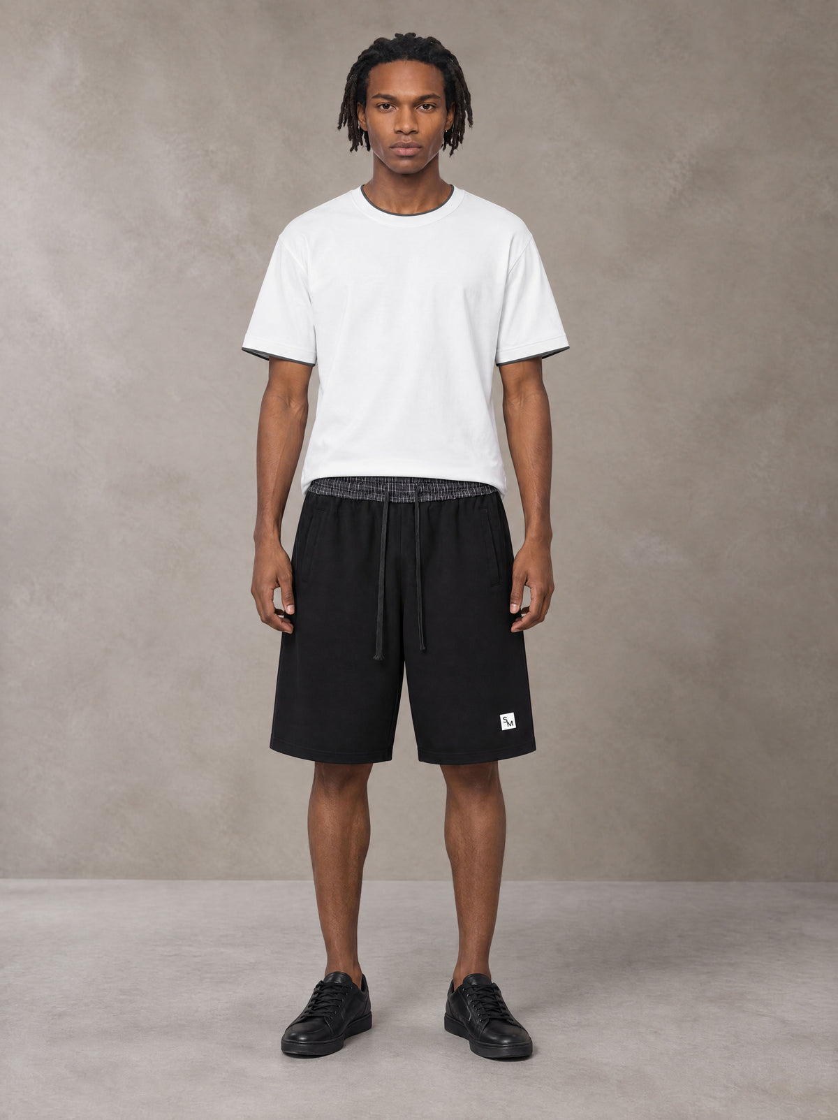 Model wearing SM Plaid Shorts in Midnight Black, front view.