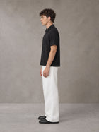 Model wearing SM Sig. Half-Zip Polo Shirt in Midnight Black, side view.