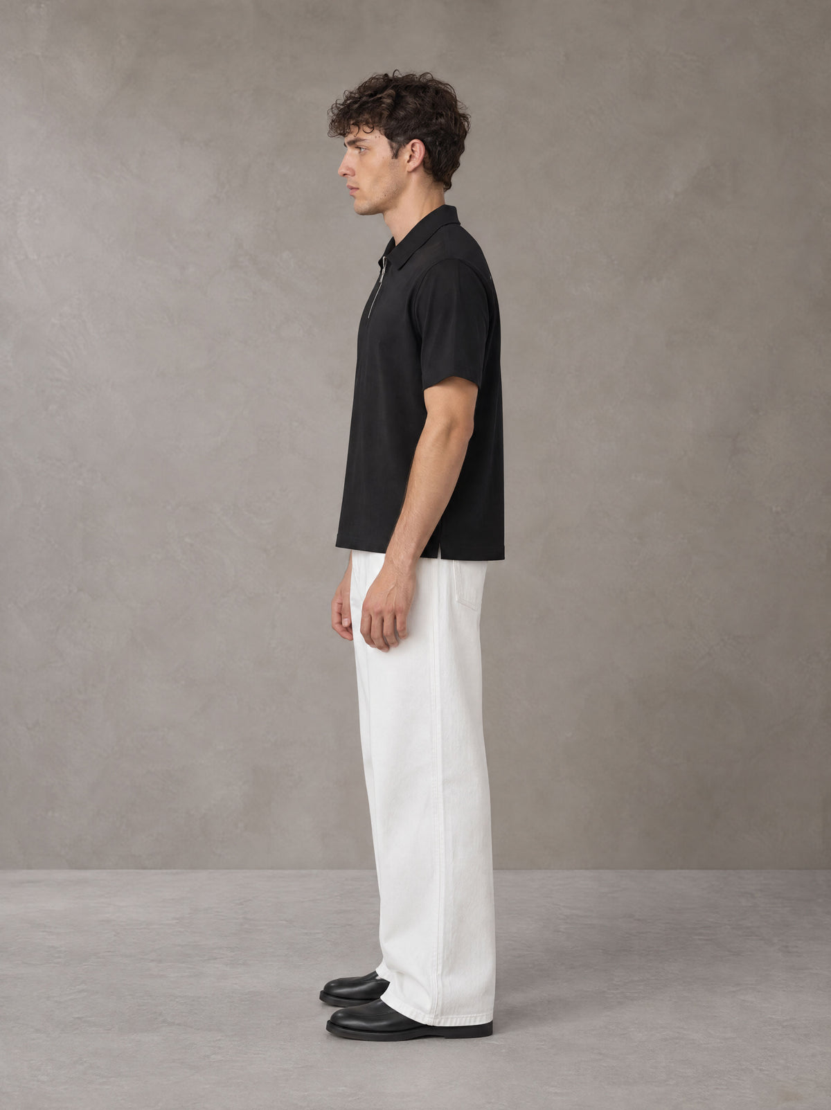 Model wearing SM Sig. Half-Zip Polo Shirt in Midnight Black, side view.