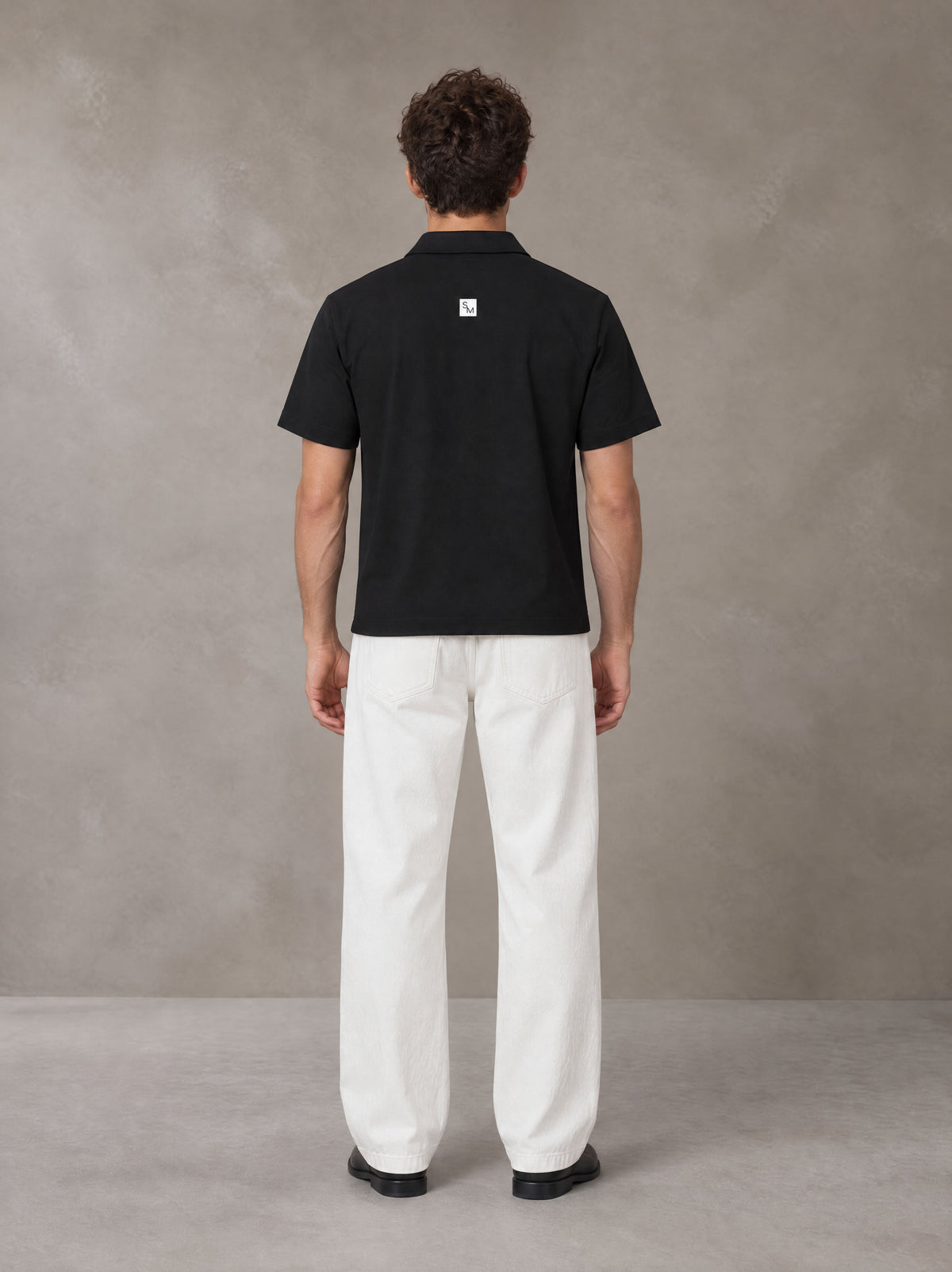Model wearing SM Sig. Half-Zip Polo Shirt in Midnight Black, rear view.