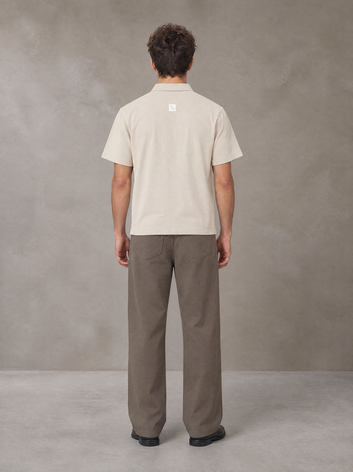 Model wearing SM Sig. Half-Zip Polo Shirt in Oatmeal Cookie, rear view.