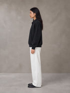 Model wearing SM Sig. Fleece Polo Sweatshirt in Midnight Black, side view.