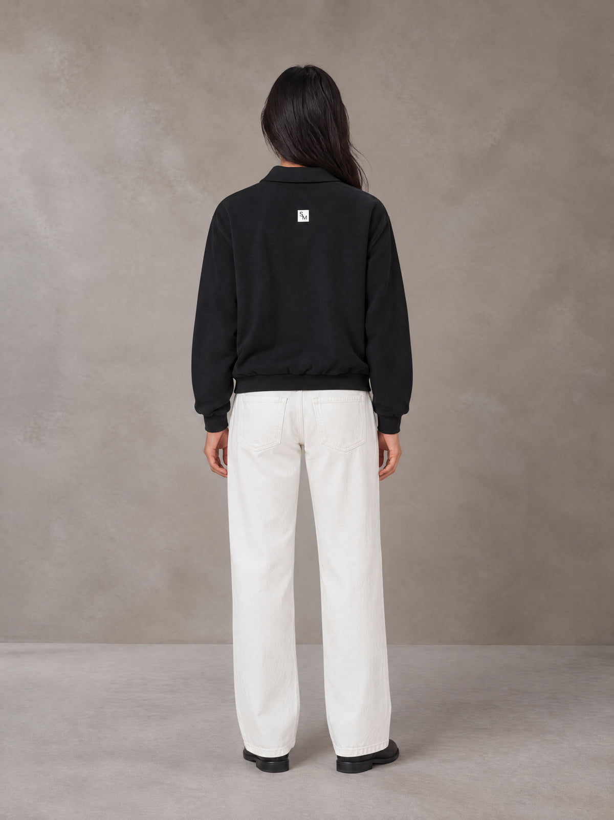 Model wearing SM Sig. Fleece Polo Sweatshirt in Midnight Black, rear view.