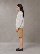 Model wearing SM Sig. Fleece Polo Sweatshirt in Oat Grey, side view.