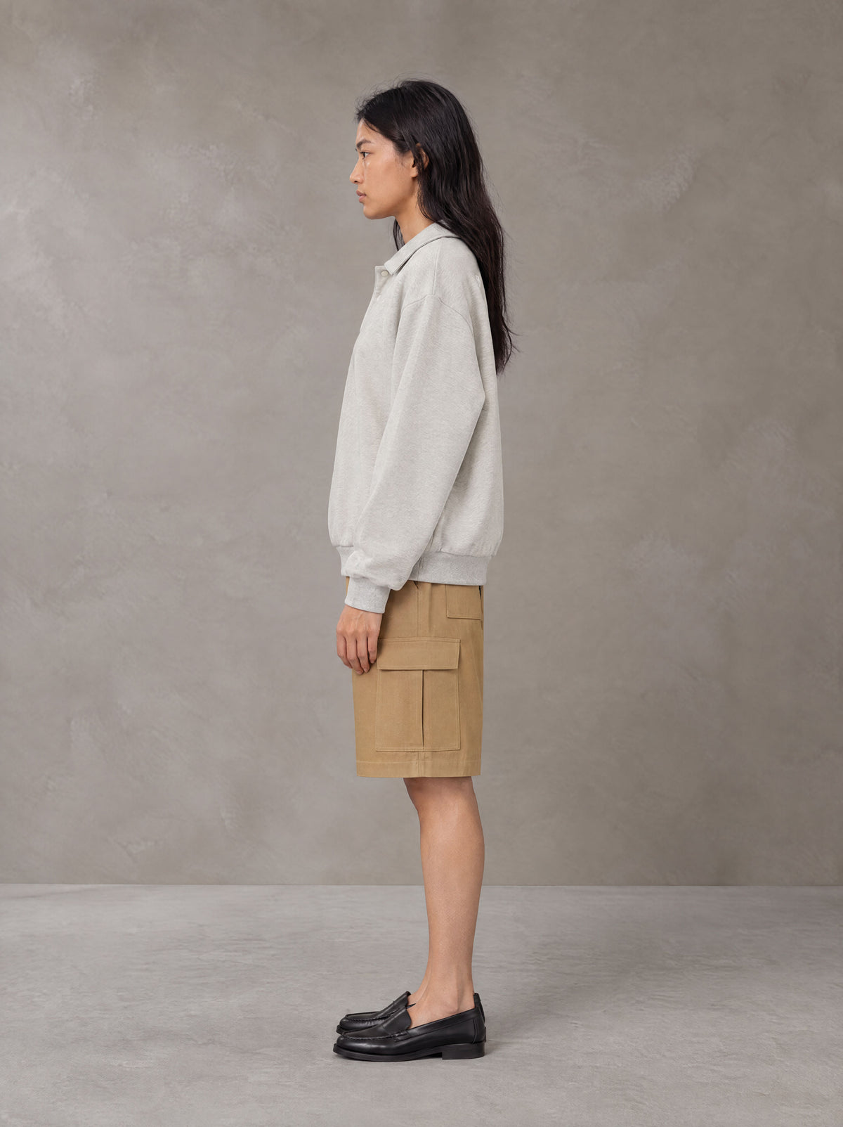 Model wearing SM Sig. Fleece Polo Sweatshirt in Oat Grey, side view.
