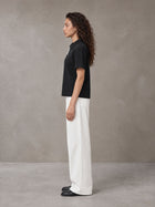 Model wearing SM Straight Leg Trousers in Lucent White, side view.