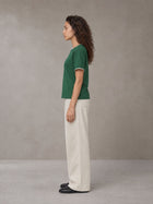 Model wearing SM Straight Leg Trousers in Oat Grey, side view.