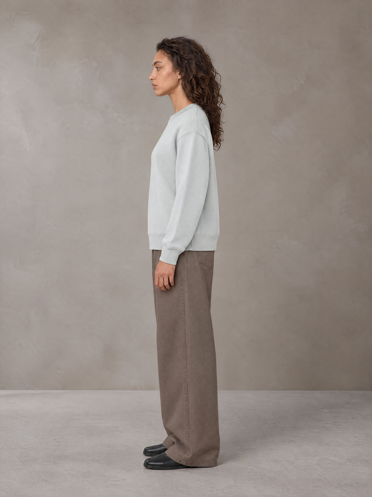 Model wearing SM Straight Leg Trousers in Kabul Brown, side view.