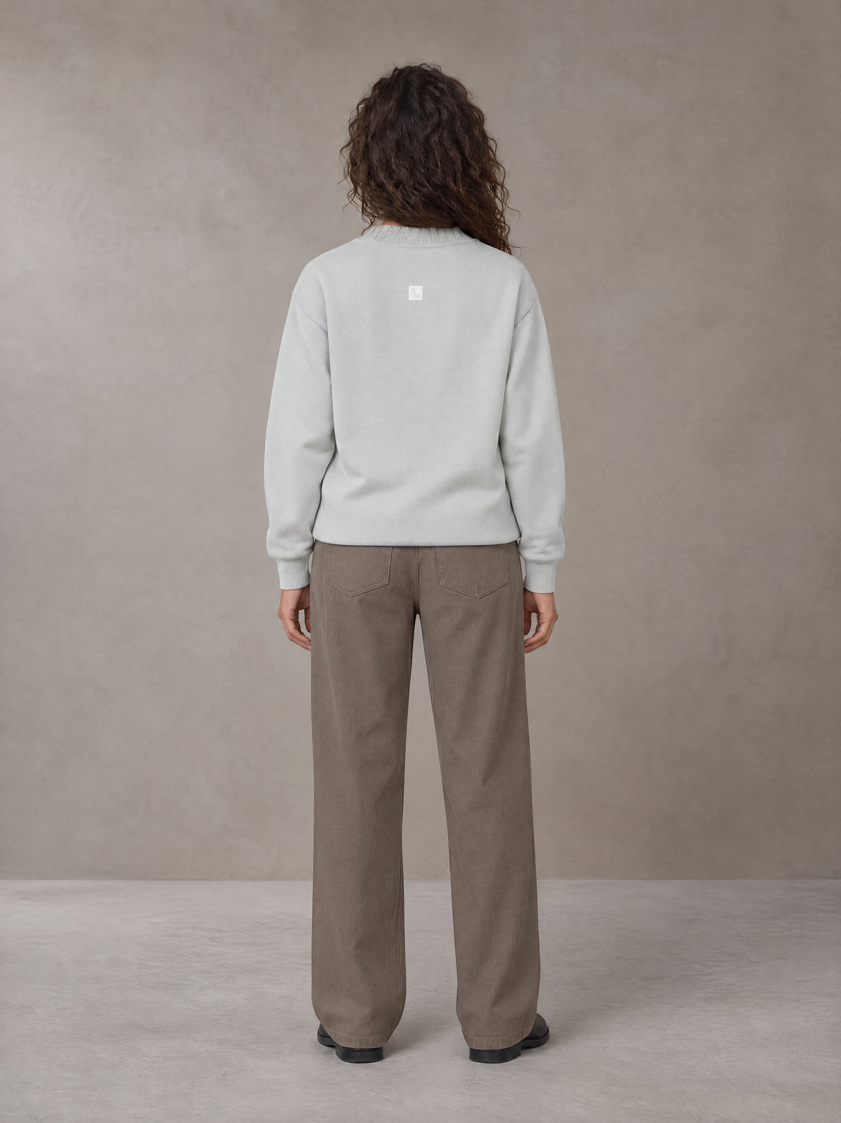 Model wearing SM Straight Leg Trousers in Kabul Brown, rear view.