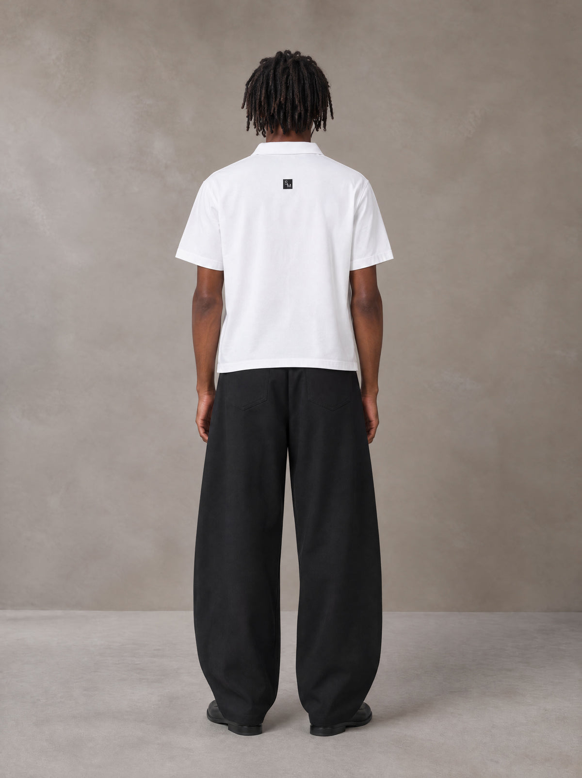 Model wearing SM Curved Trousers in Midnight Black, rear view.
