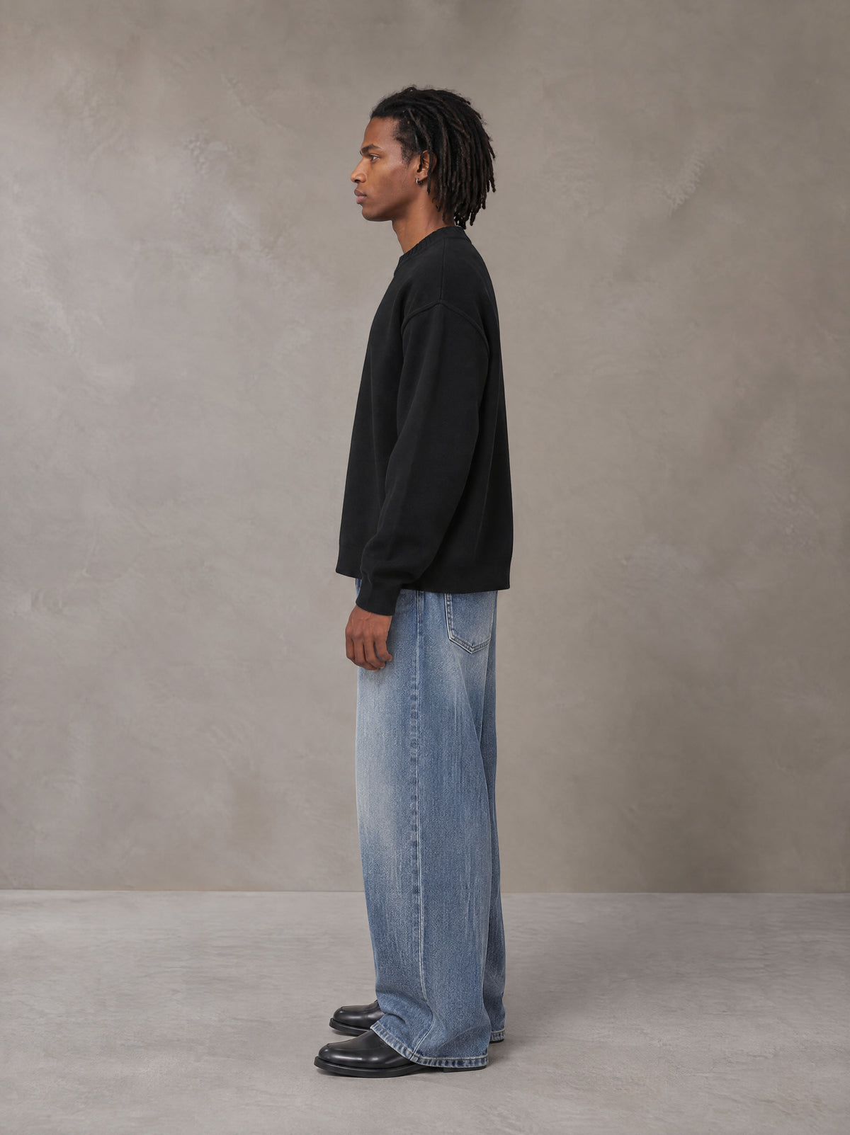 Model wearing SM Sig. Knitted Round Neck Sweatshirt in Midnight Black, side view.