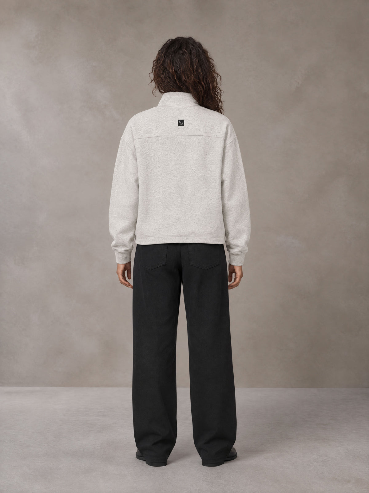 Model wearing SM Sig. Half-Zip Fleece Sweatshirt in Oat Grey, rear view.