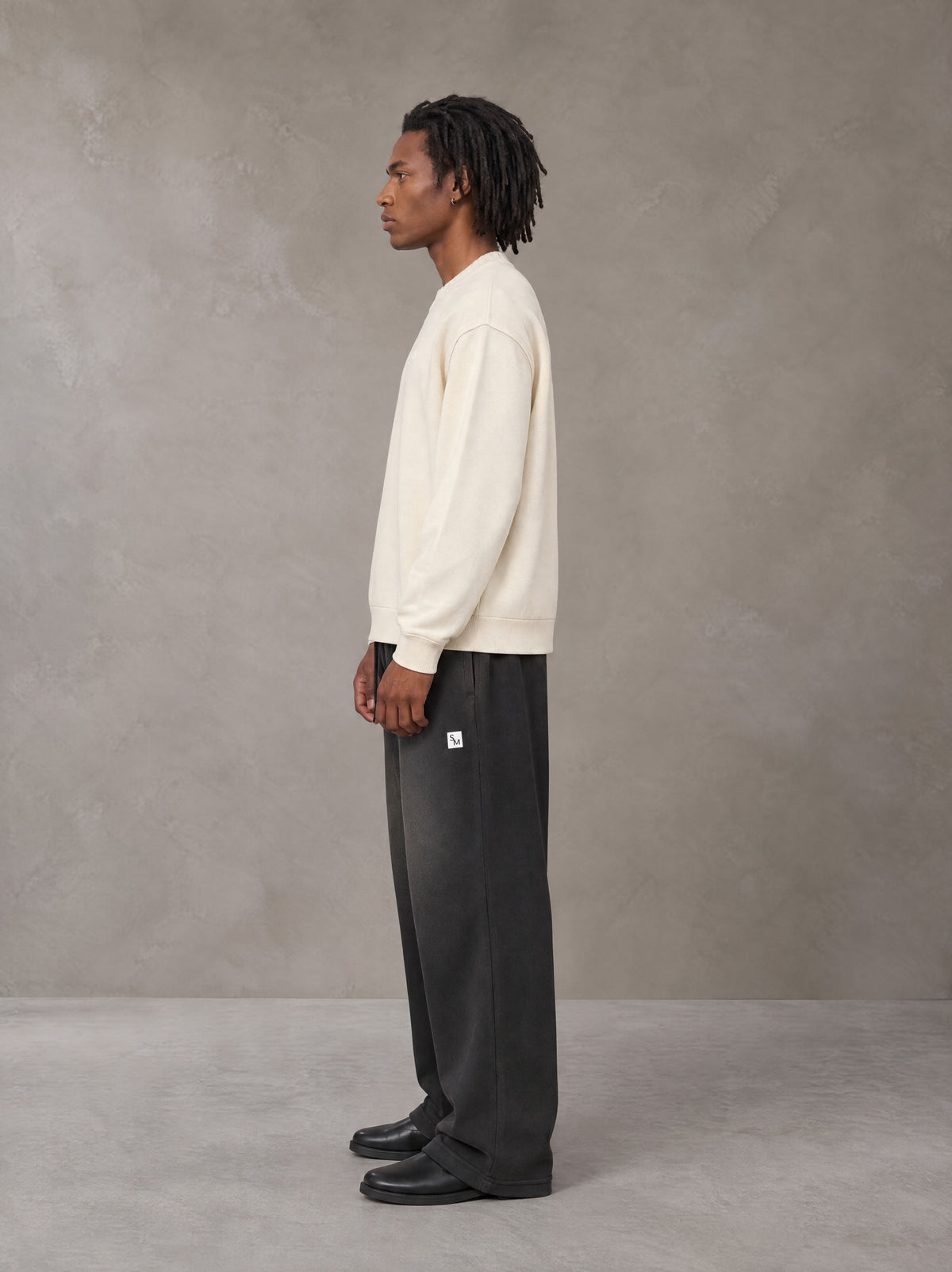 Model wearing SM Sig. Sun Fade Sweatpants in Midnight Black, side view.