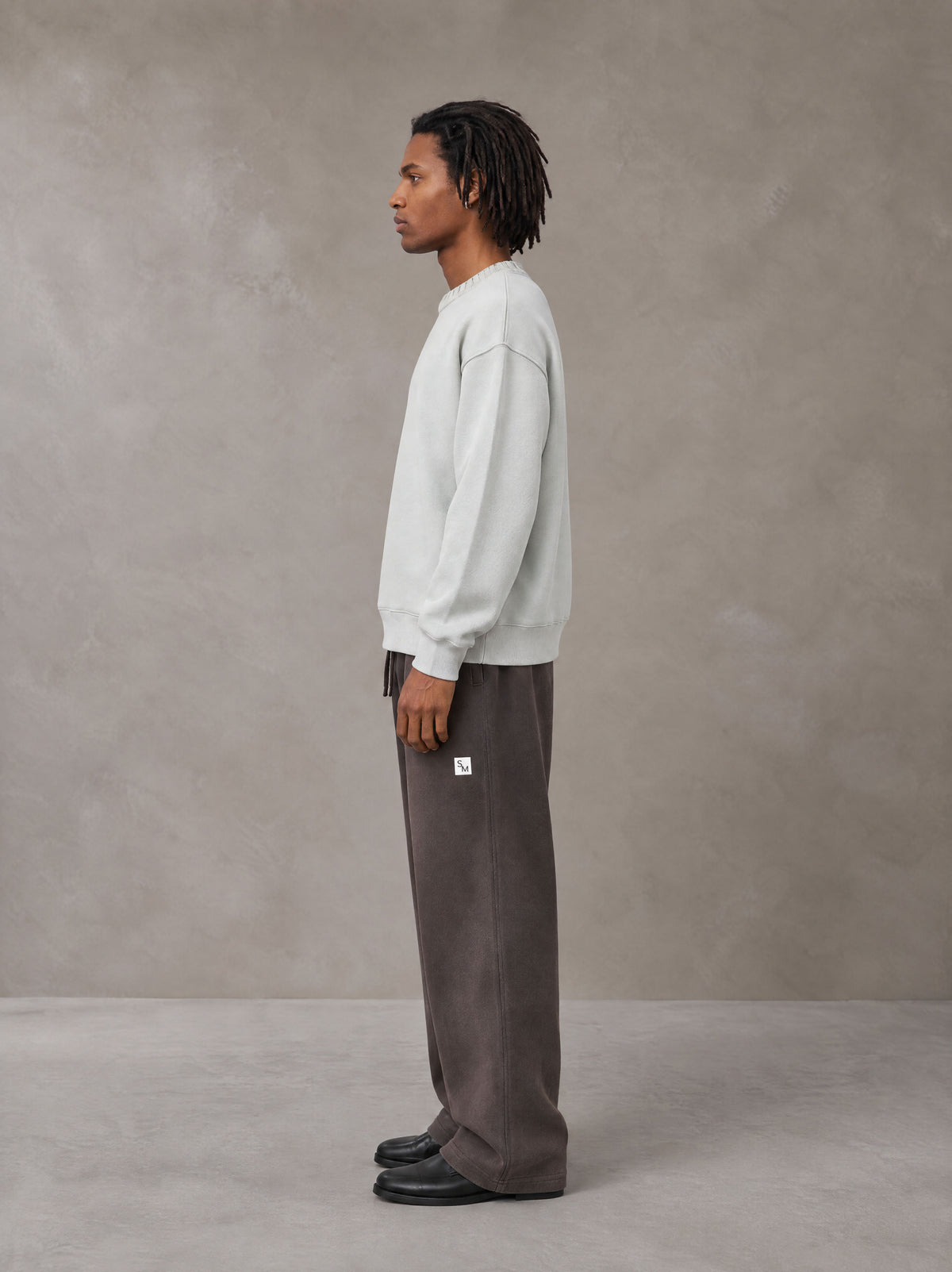 Model wearing SM Sig. Sun Fade Sweatpants in Kabul Brown, side view.