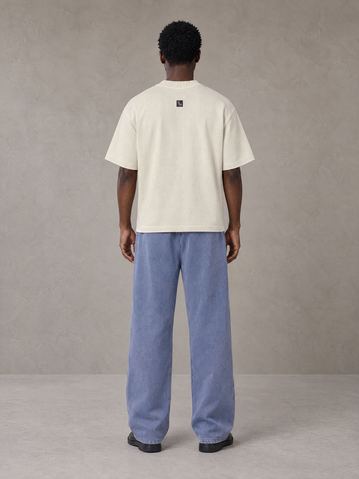 Model wearing SM Snow Fade Sweatpants in Chambray, rear view.