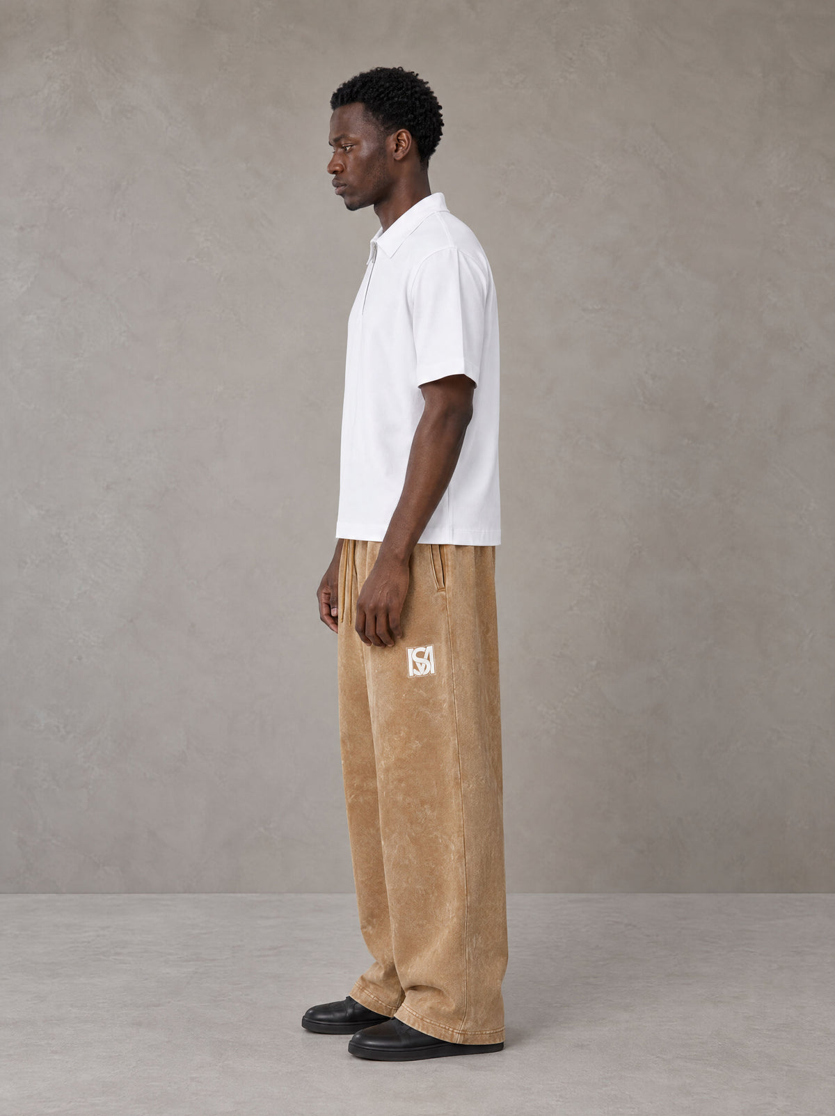 Model wearing SM Snow Fade Sweatpants in Aged Whiskey, side view.