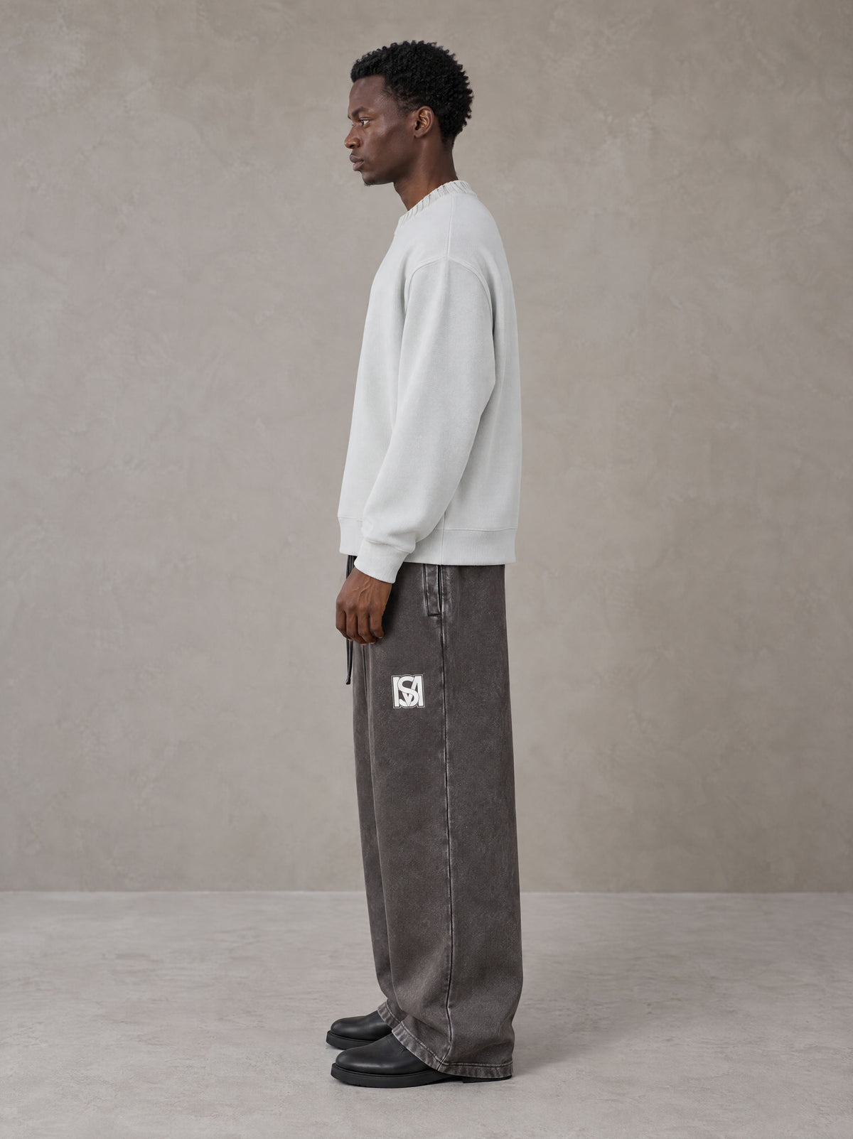 Model wearing SM Snow Fade Sweatpants in Graphite, side view.