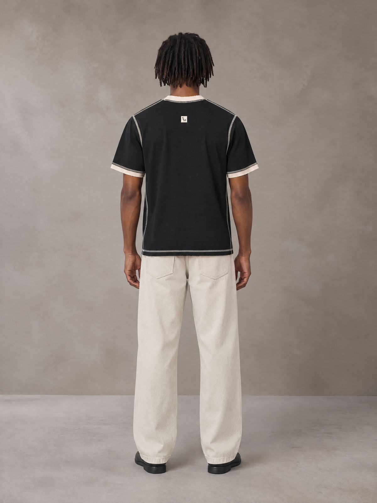 Model wearing SM Sig. Contrast Stitch T-shirt in Midnight Black, rear view.