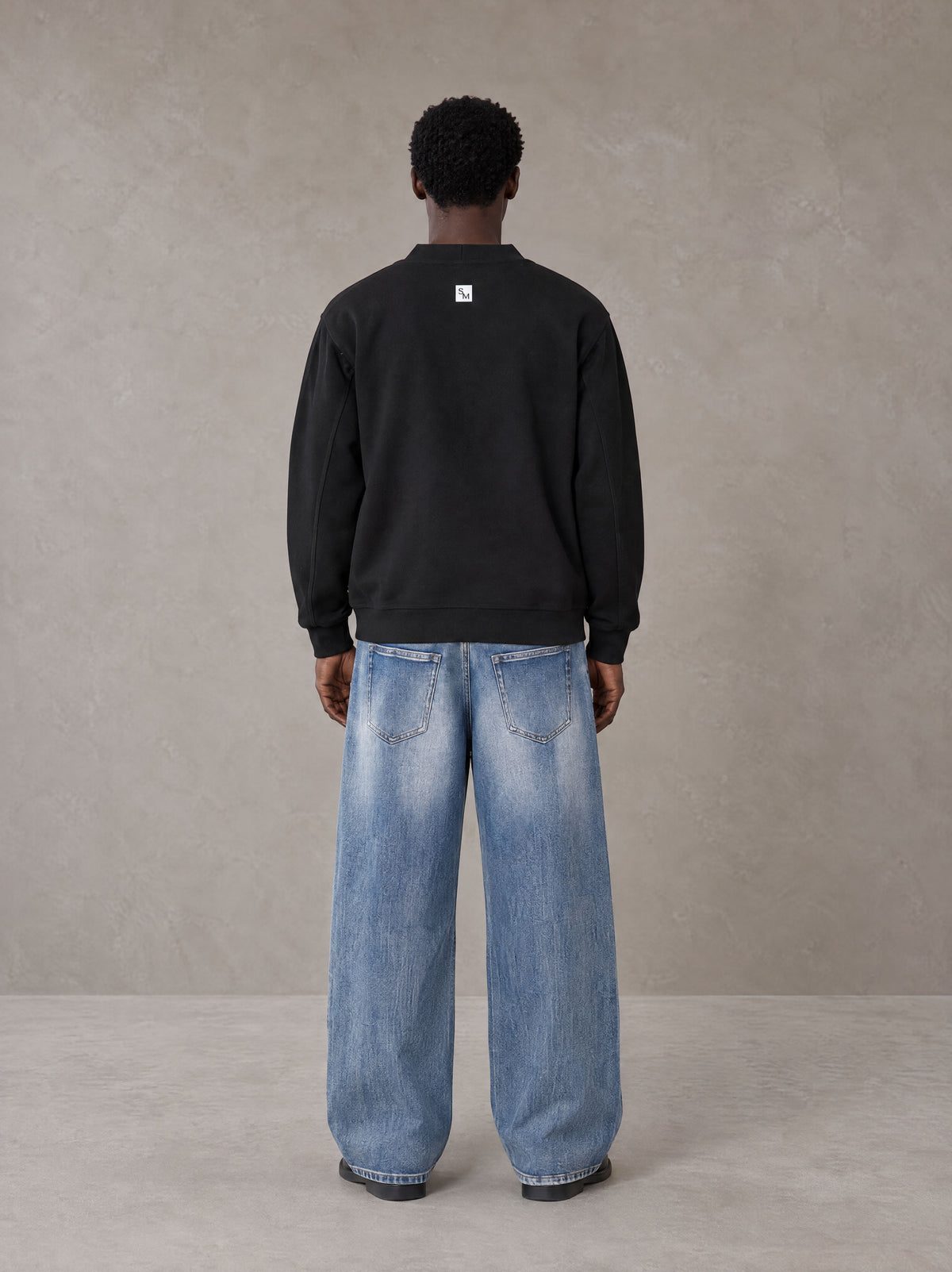 Model wearing SM Sig. Cardigan in Midnight Black, rear view.